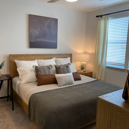 Bed with pillows in a model home's bedroom at Center West Apartments in Midlothian, Virginia