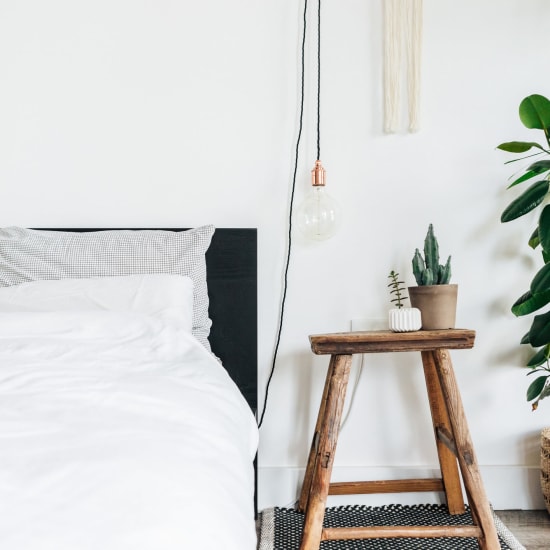 Bed and nightstand in a model home's bedroom at Sharp Leadenhall Apartments in Baltimore, Maryland