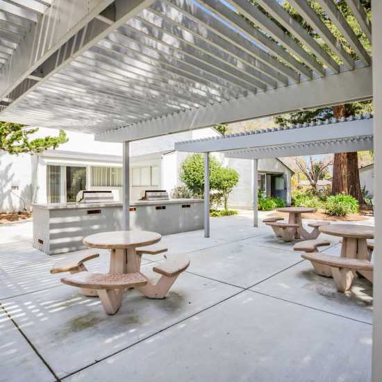 Community sitting area with tables and BBQ grills at Capitola Gardens in Capitola, California
