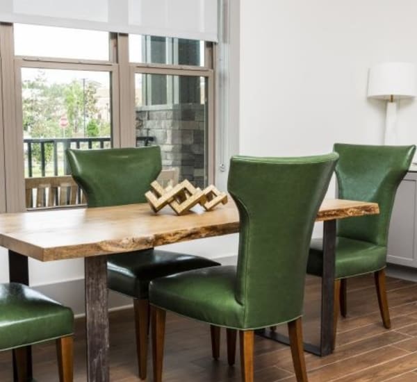 A dining room set with green chairs by large windows at Retreat at Fairhope Village in Fairhope, Alabama Retreat at Fairhope Village in Fairhope, Alabama