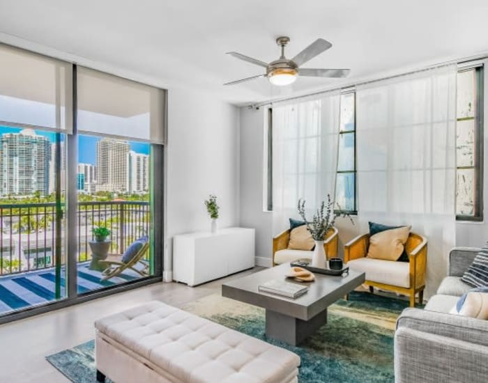 An apartment living room with wood-style flooring and a sliding door to the balcony at Marina Del Viento in Sunny Isles Beach, Florida