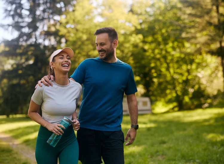 Garden style smiling couple walking together in green park at 15-25 Hemenway Apartments in Boston, Massachusetts