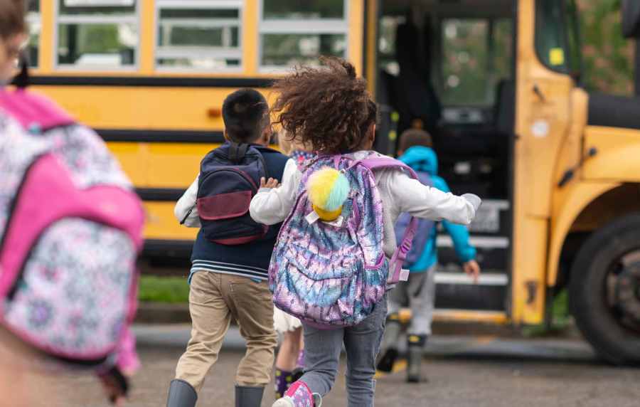 Resident children running joyfully towards their school bus near Victoria Park Apartments in Davenport,Florida