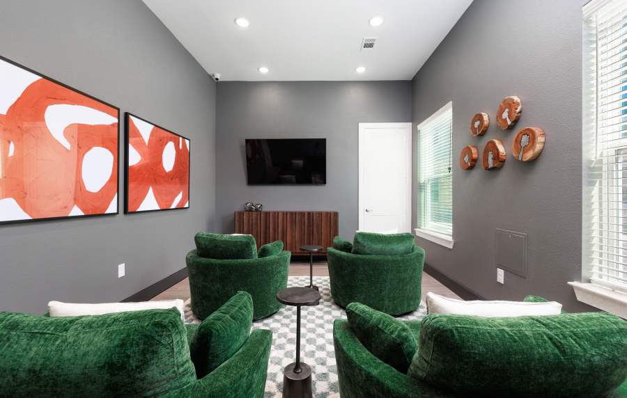 Cozy lounge area with green chairs, modern decor, and a large TV on the wall at Sankofa Landing in Durham, North Carolina