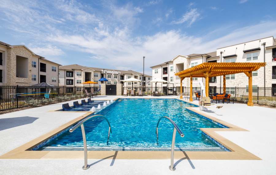 Resort-style pool with lounge chairs and shaded seating area under pergola at Preserve at Gresham Lake in Raleigh, North Carolina