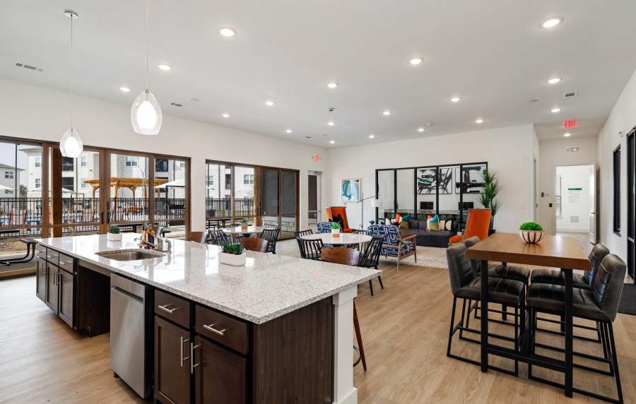 Bright community lounge with granite island, wood-style flooring, and modern seating areas at Preserve at Gresham Lake in Raleigh, North Carolina