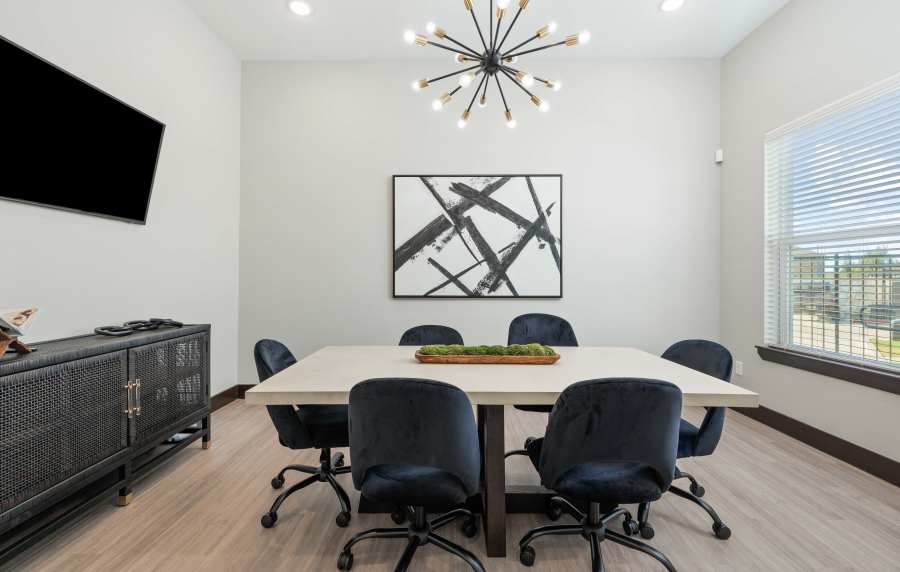 Modern community room with a large table, stylish chairs, and a decorative light fixture at Preserve at Gresham Lake in Raleigh, North Carolina