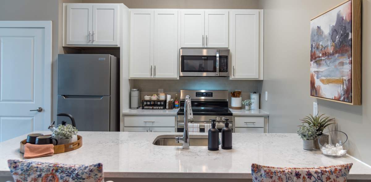 Beautiful kitchen with kitchen counter as table with chairs at Acclaim at Cary Pointe in Cary, North Carolina