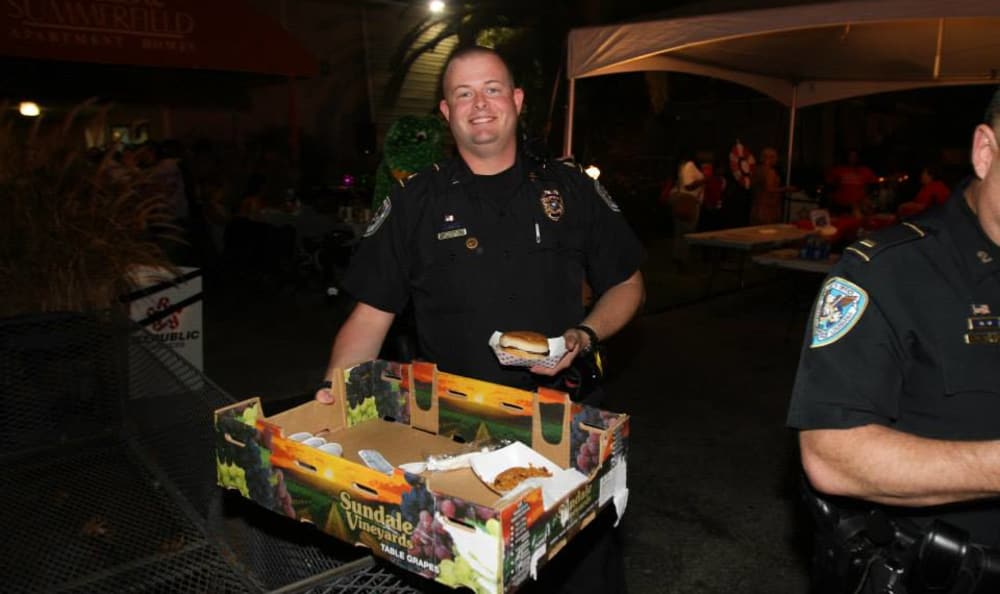 Policeman giving out food at Emerald Pointe Apartment Homes in Harvey, Louisiana
