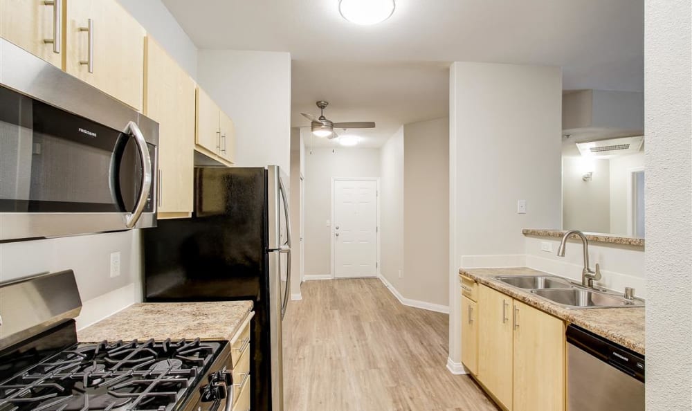 Stainless-steel appliances and hardwood flooring in a model home's kitchen at Sierra Oaks Apartments in Turlock, California