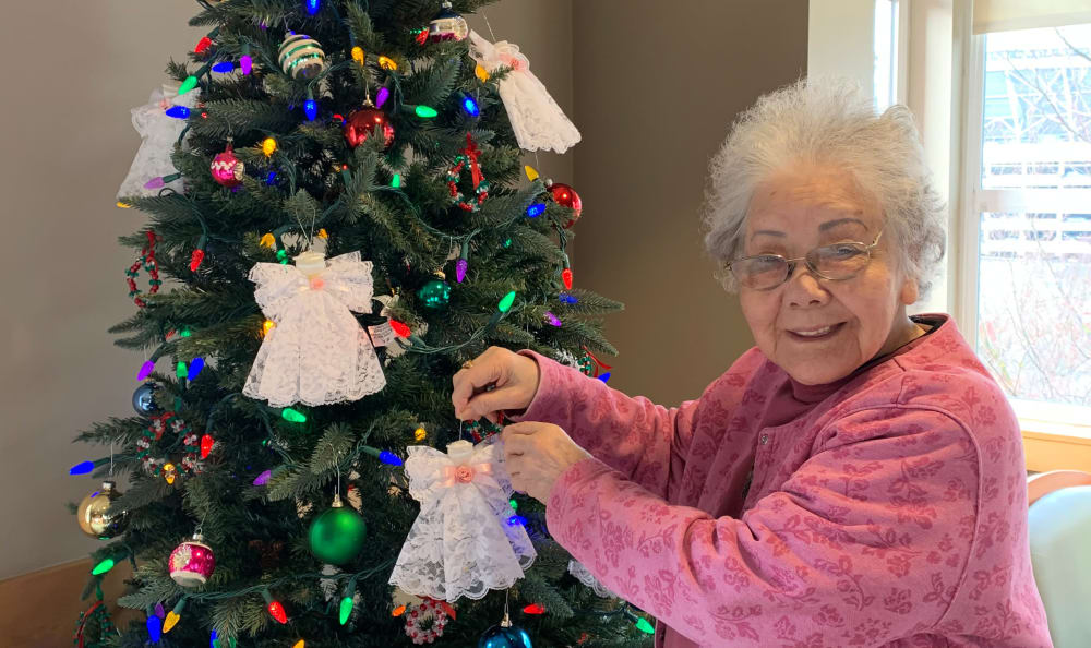 A resident putting an ornament on a Christmas tree at Nikkei Manor in Seattle, WA
