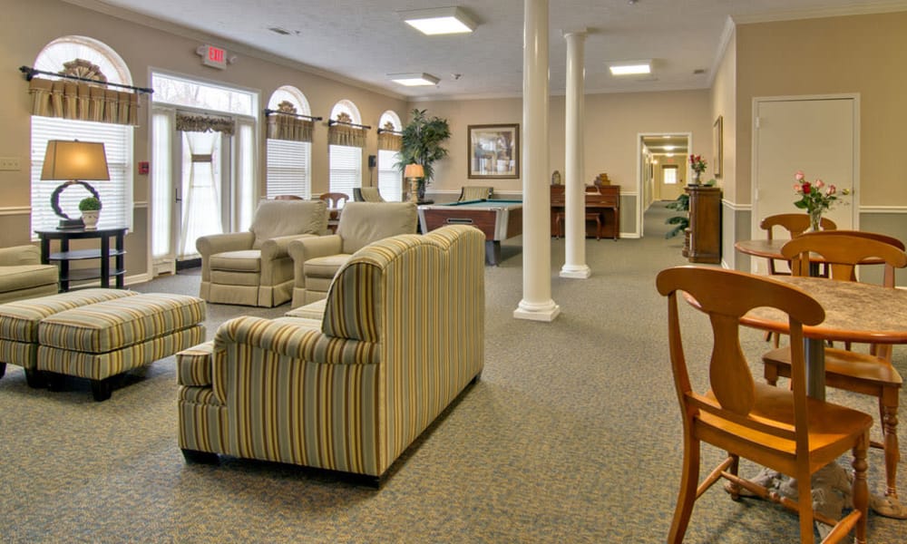 Community lounge with comfortable seating next to the game room at Harmony Hill in Huntingdon, Tennessee