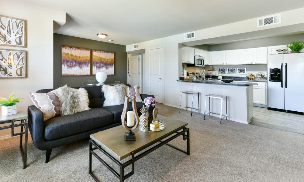 Bright, well decorated living room with plush carpeting at Cottages at Abbey Glen Apartments in Lubbock, Texas