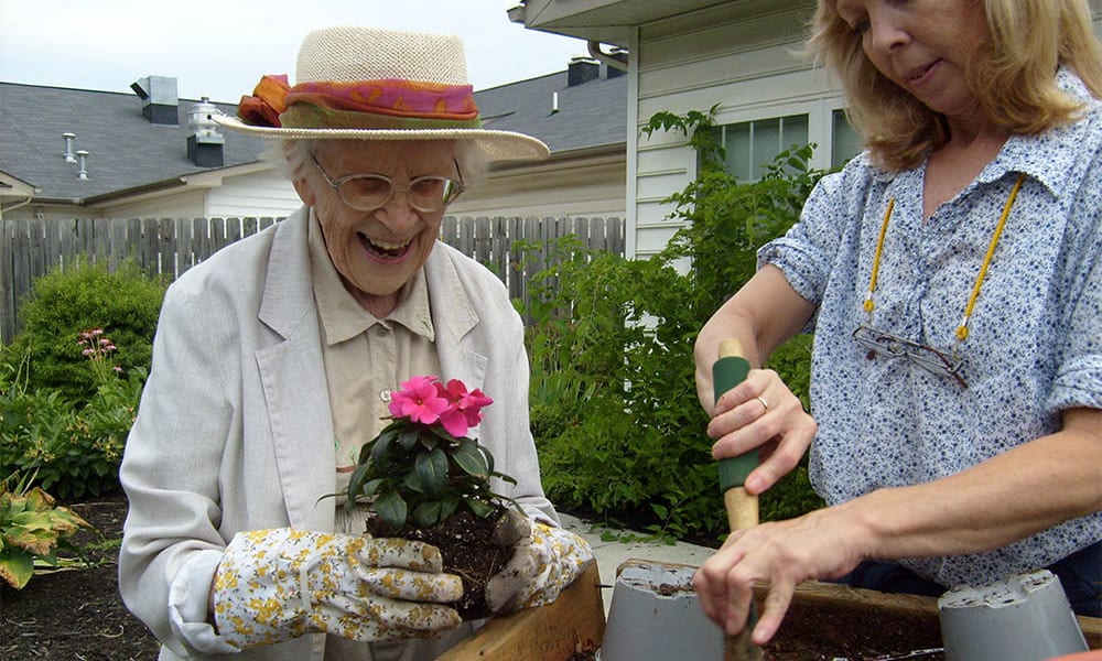 Two residents gardening in a planter box at Heritage Green Assisted Living and Memory Care in Lynchburg, Virginia