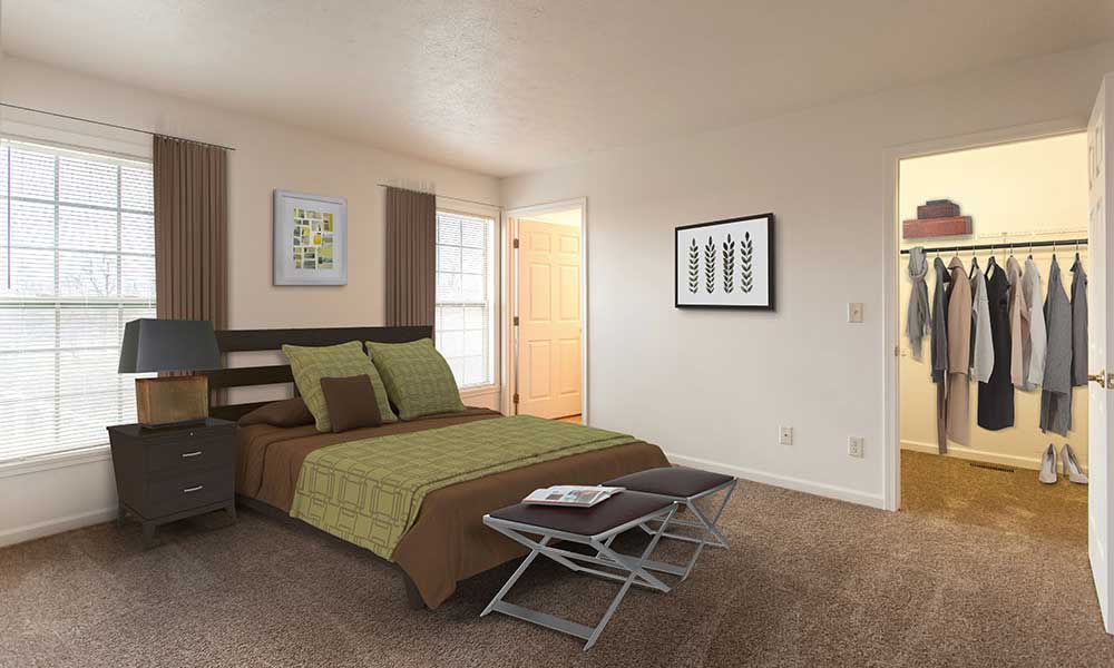 Model bedroom with plush carpeting and a walk-in closet at Hickory Hollow in Spencerport, New York