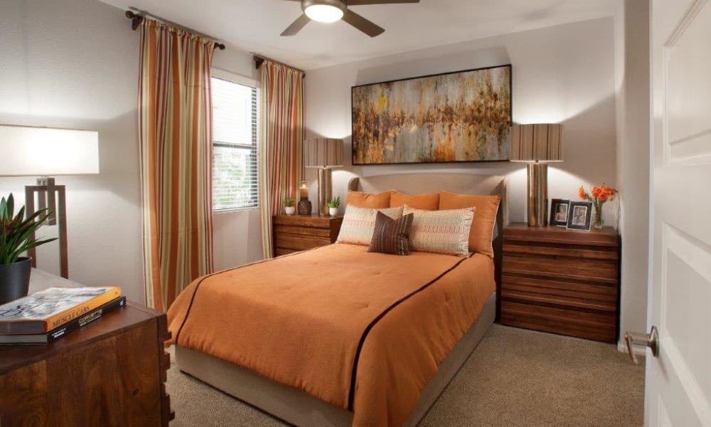 Well-furnished primary bedroom with draped windows in a model apartment at Vive in Chandler, Arizona