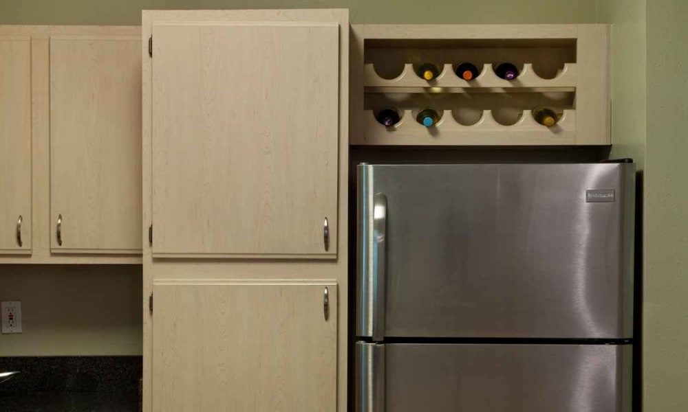 Built-in wine rack above the stainless-steel refrigerator in a model apartment at Wimberly at Deerwood in Jacksonville, Florida