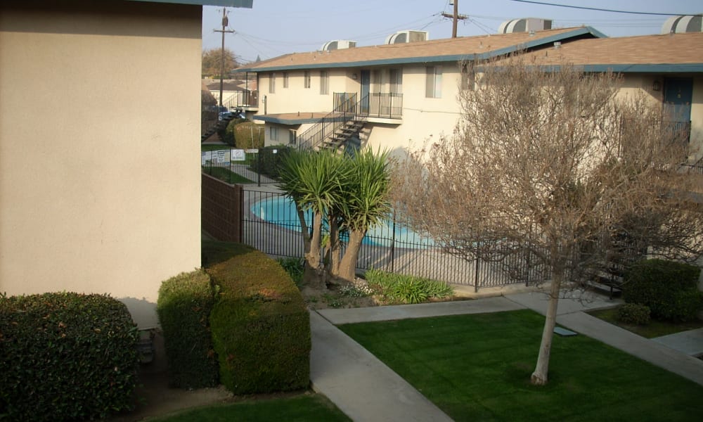View of building exteriors, landscape, and pool at Highland View Court in Bakersfield, California