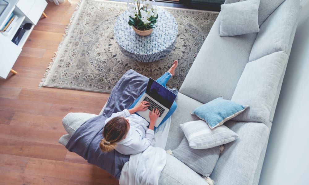 Resident working on her laptop while relaxing on the couch in the living room at Lehigh Valley in Whitehall, Pennsylvania