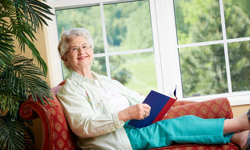 Resident laying by a sunlit windowsill reading a book at Deer Crest Senior Living in Red Wing, Minnesota