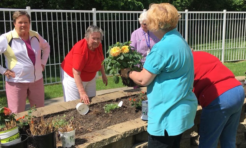 Group of active residents plating flowers outside at Deer Crest Senior Living in Red Wing, Minnesota