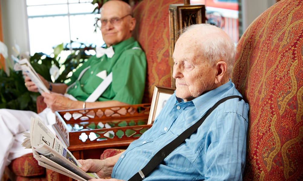 Two residents sitting and reading the newspaper at Deer Crest Senior Living in Red Wing, Minnesota