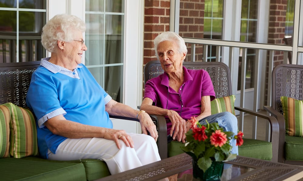 Two residents sitting on the porch and talking at Deer Crest Senior Living in Red Wing, Minnesota