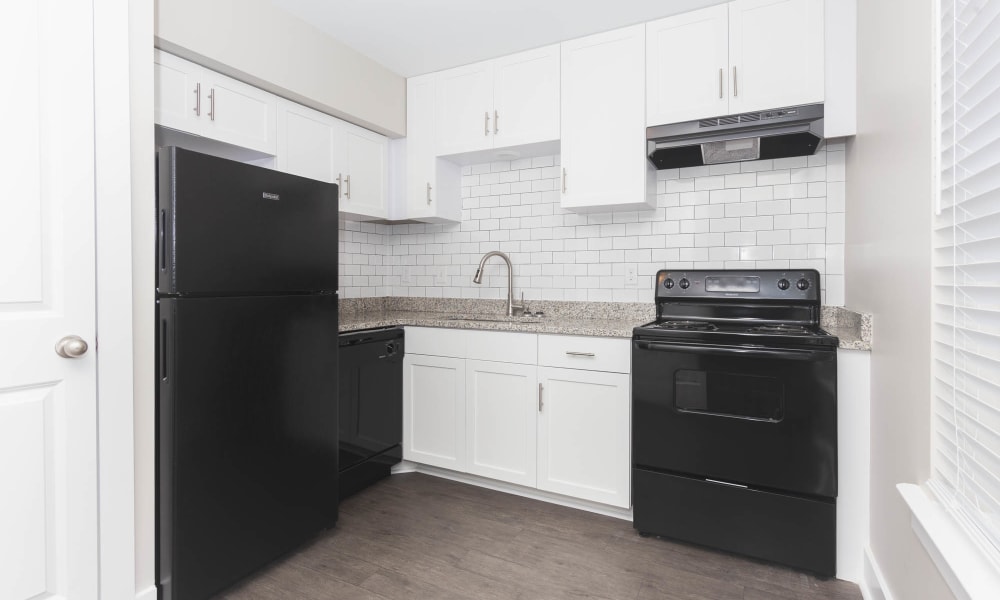 Kitchen with white cabinets, granite countertops, subway tile backsplash and black appliances The Hills at Oakwood Apartment Homes in Chattanooga, Tennessee