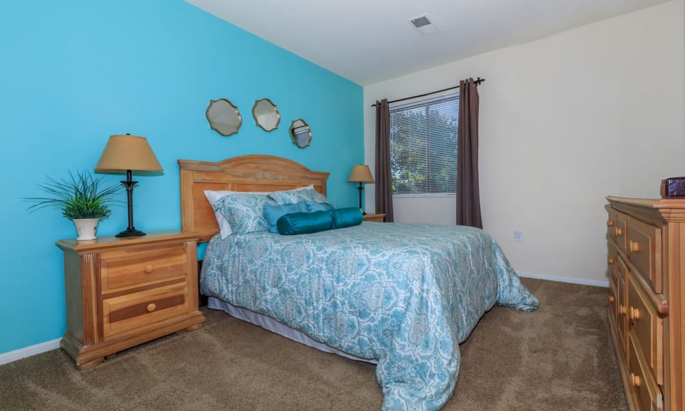 Carpeted model bedroom with a blue accent wall at Lakeside Crossing at Eagle Creek in Indianapolis, Indiana