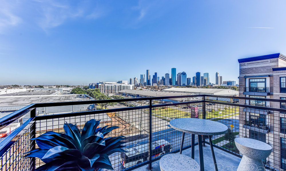 Apartment balcony with plant and patio furniture at Bellrock Sawyer Yards in Houston, Texas
