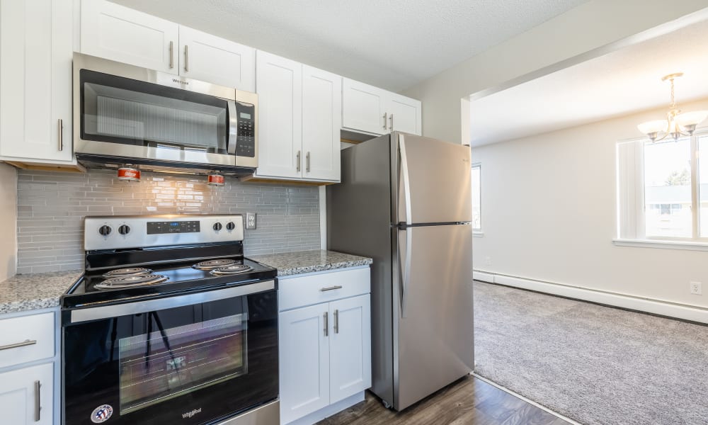 Modern kitchen with white cabinets and stainless steel appliances at Long Pond Gardens Senior Apartments in Rochester, New York