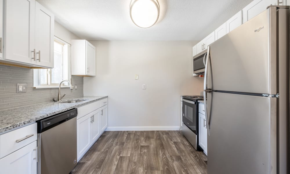 Fully equipped kitchen with wood-style plank flooring and stainless-steel appliances at Long Pond Gardens Senior Apartments in Rochester, New York