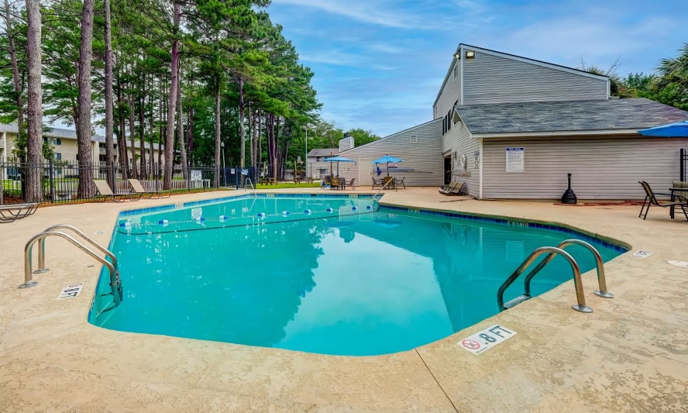Swimming pool and pool deck with clubhouse in background at Forestbrook Apartments & Townhomes in West Columbia, South Carolina