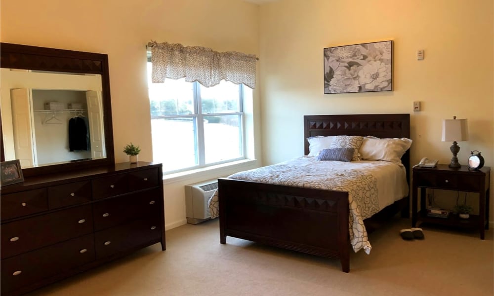 Resident apartment bedroom with full bed and matching wooden dresser and nightstand at The Birches of Lehigh Valley in Easton, Pennsylvania