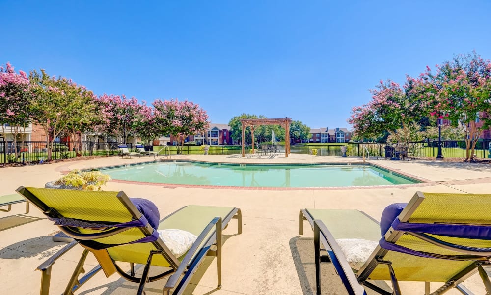 Patio chairs next to the outdoor pool at Champion Lake Apartment Homes