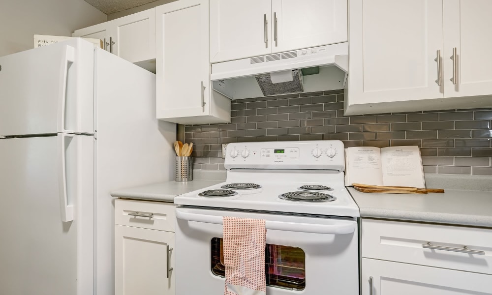 Updated kitchen with white cabinets, tile backsplash, and white appliances Lakewood Apartment Homes in Salisbury, North Carolina