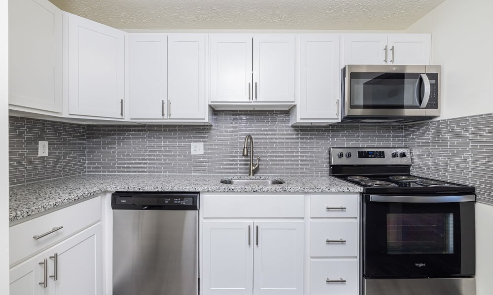 Updated kitchen with white cabinets, tile backsplash, and white appliances Westpointe Apartments in Pittsburgh, Pennsylvania