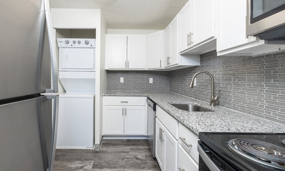 Updated kitchen with white cabinets, tile backsplash, and white appliances Westpointe Apartments in Pittsburgh, Pennsylvania