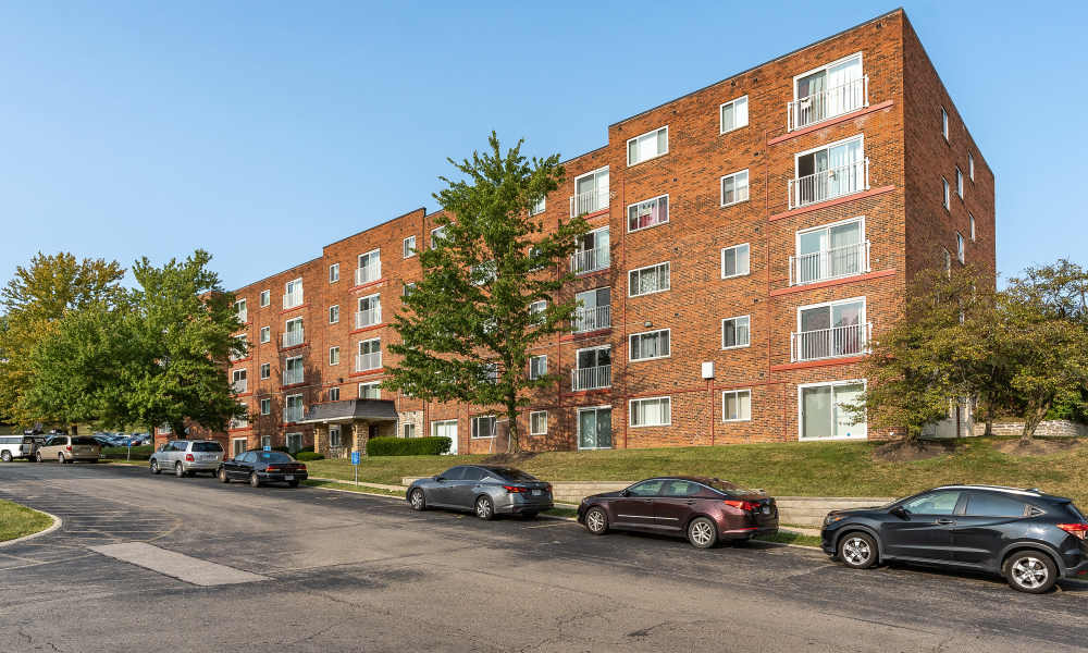 Exterior shot of the building with multiple cars parked in front of the building at Vantage Pointe West Apartment Homes in Cincinnati, Ohio