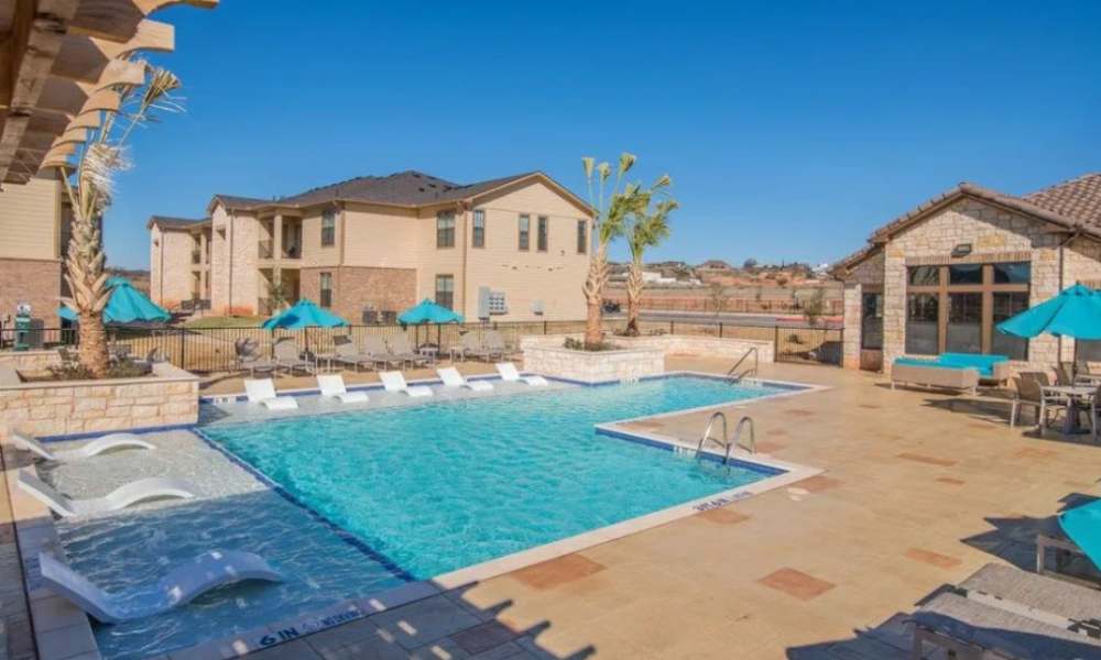 Resort style swimming pool with lounge seating and canopy at Vistas at Red Creek in , Texas