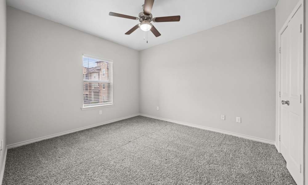 Carpeted bedroom with lighted ceiling fan and window at Sunset Lodge in Odessa, Texas