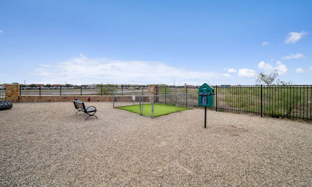 Fenced dog park with pet waste station and bench at Sunset Lodge in Odessa, Texas