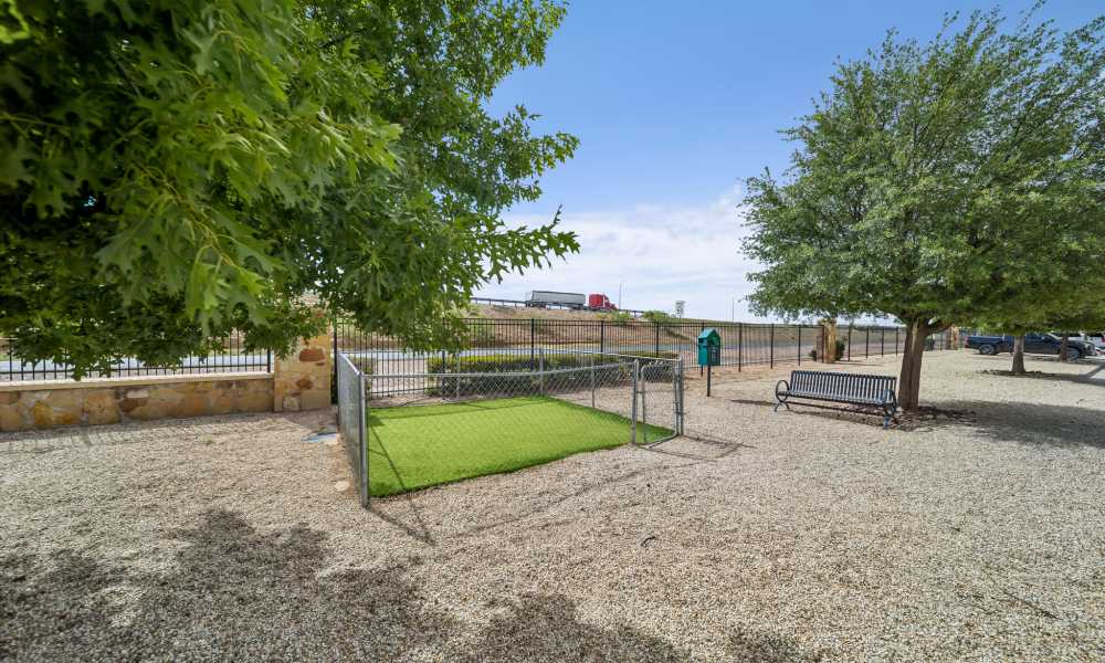 Fenced dog park surrounded by trees at Sunset Lodge in Odessa, Texas