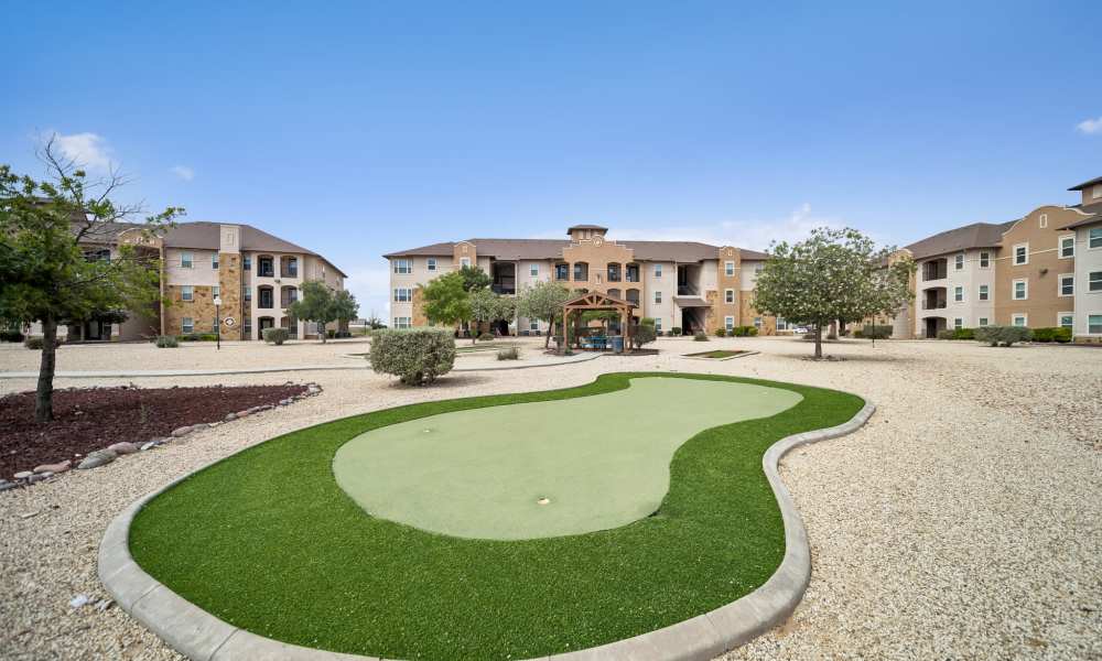 Close-up of putting green with apartment buildings in the background at Sunset Lodge in Odessa, Texas