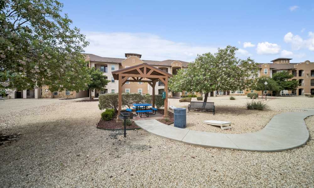 Outdoor pergola with picnic table, bbq grill, and winding sidewalk at Sunset Lodge in Odessa, Texas