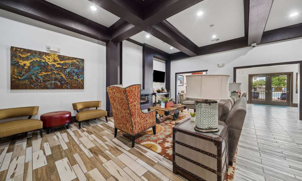 Well decorated clubhouse seating area with mounted TV and front entry in background at Sunset Lodge in Odessa, Texas