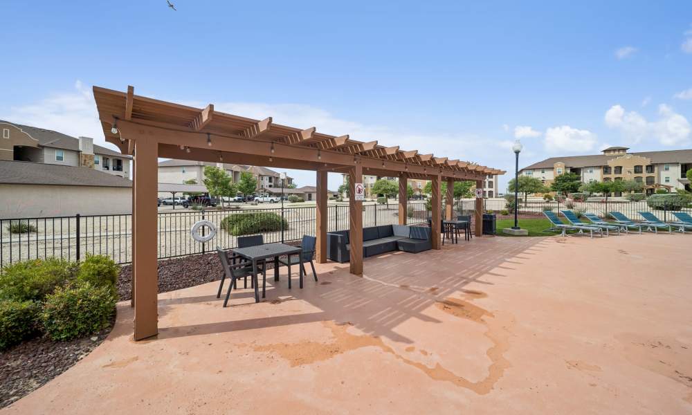 Pergolas with picnic tables and couches in pool area at Sunset Lodge in Odessa, Texas