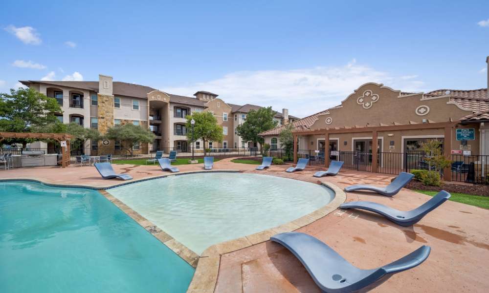View of the shallow area of the swimming pool surrounded by chaise lounges at Sunset Lodge in Odessa, Texas
