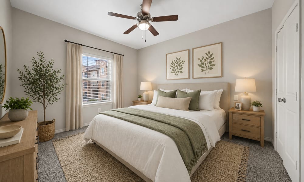 Furnished, carpeted bedroom with lighted ceiling fan and window at Sunset Lodge in Odessa, Texas
