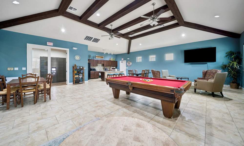 Pool table with dining area and clubhouse kitchen in background at Vistas at Red Creek in San Angelo, Texas